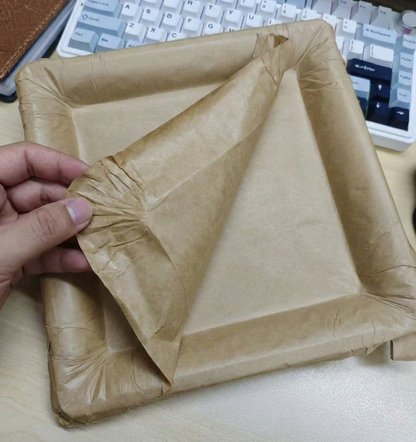A hand peeling the top layer of a multi-layered paper plate to reveal a clean surface underneath